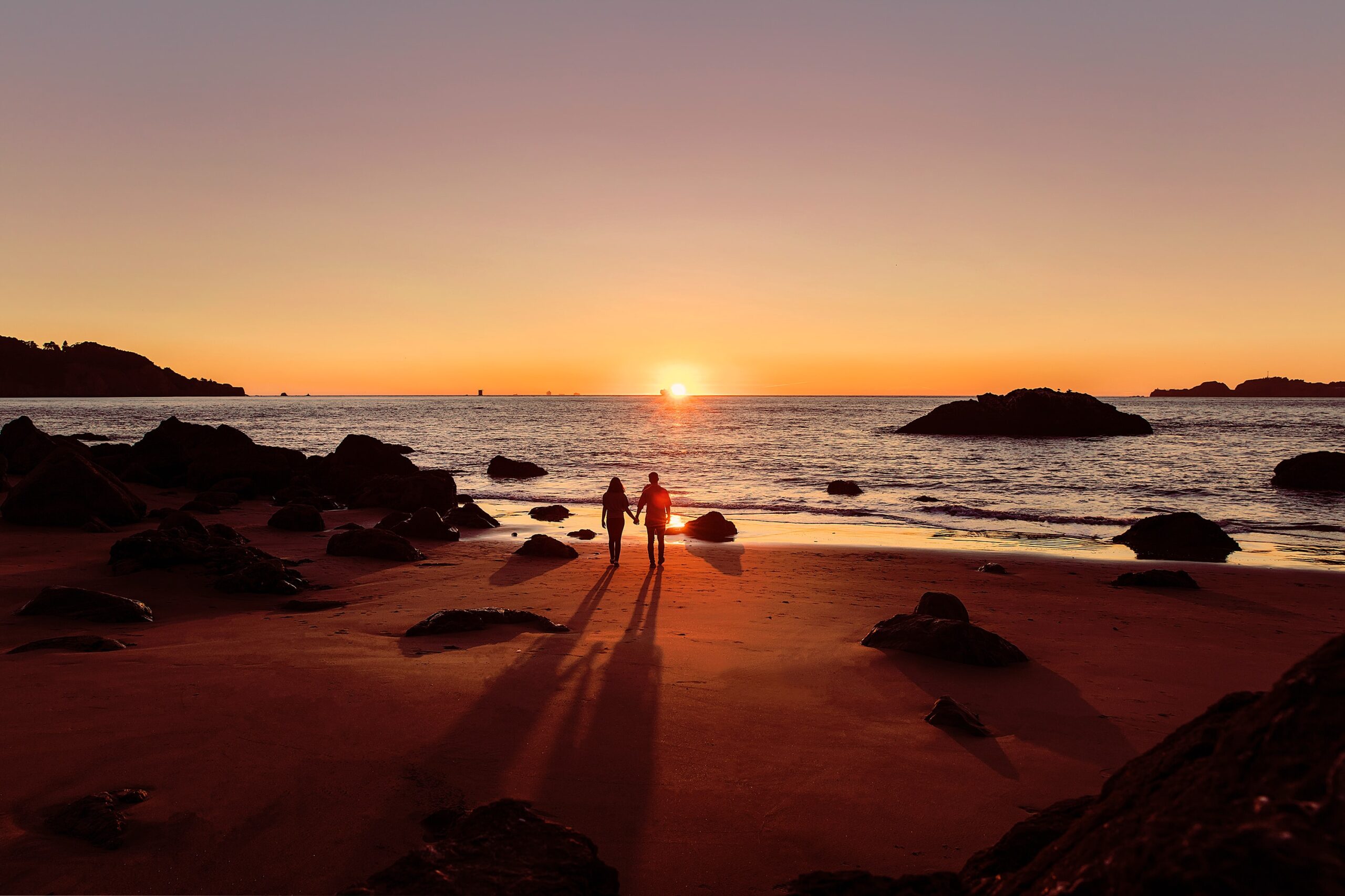 Couple walking on a date at sunset in Baker Beach