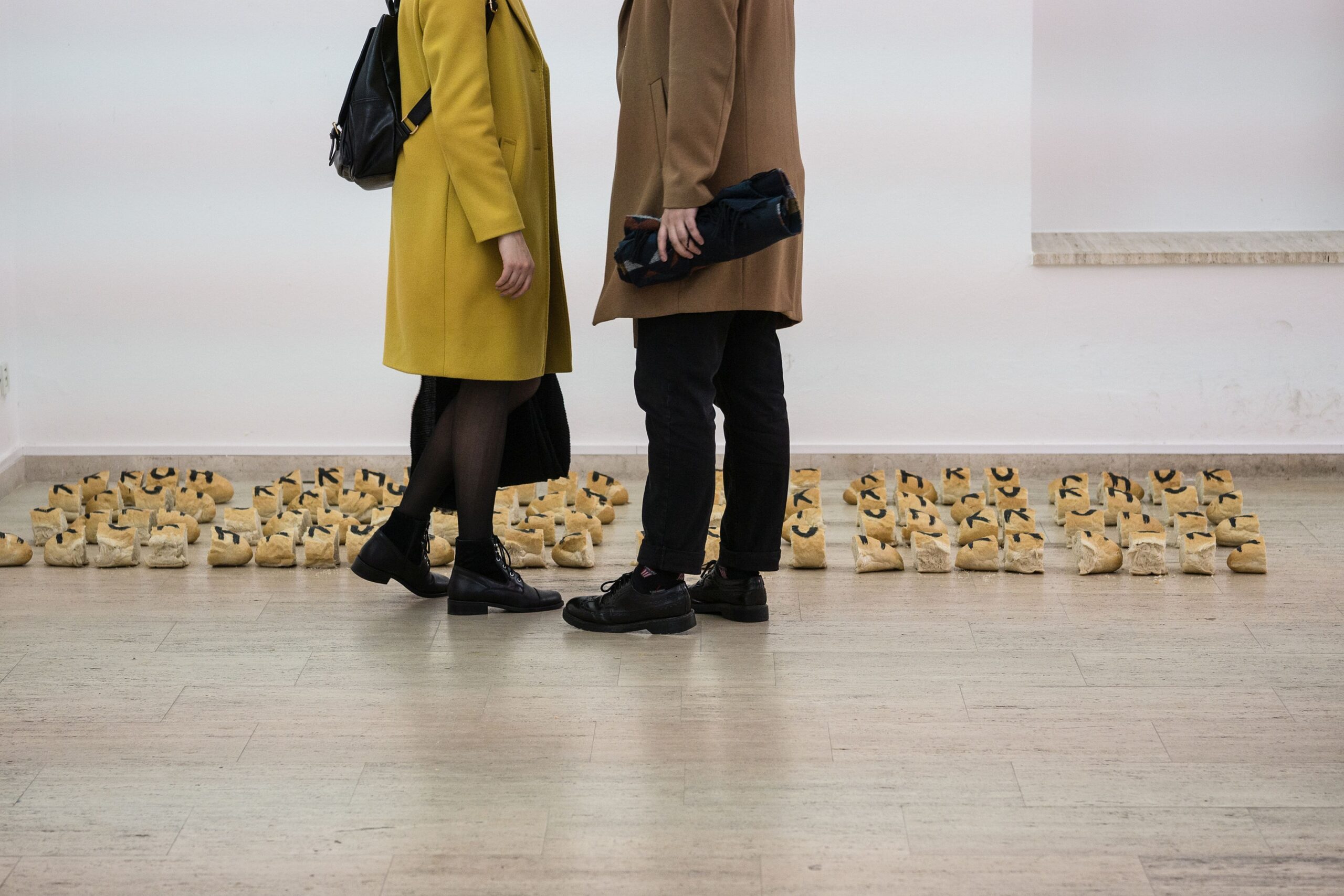 Bottom half of couple looking at art in a gallery