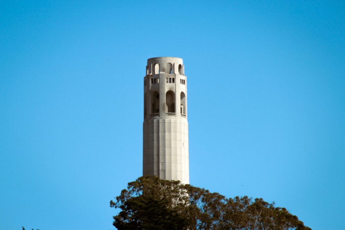 Close-up view of Coit Tower's distinctive Art Deco architecture with observation deck and arched windows against clear blue San Francisco sky