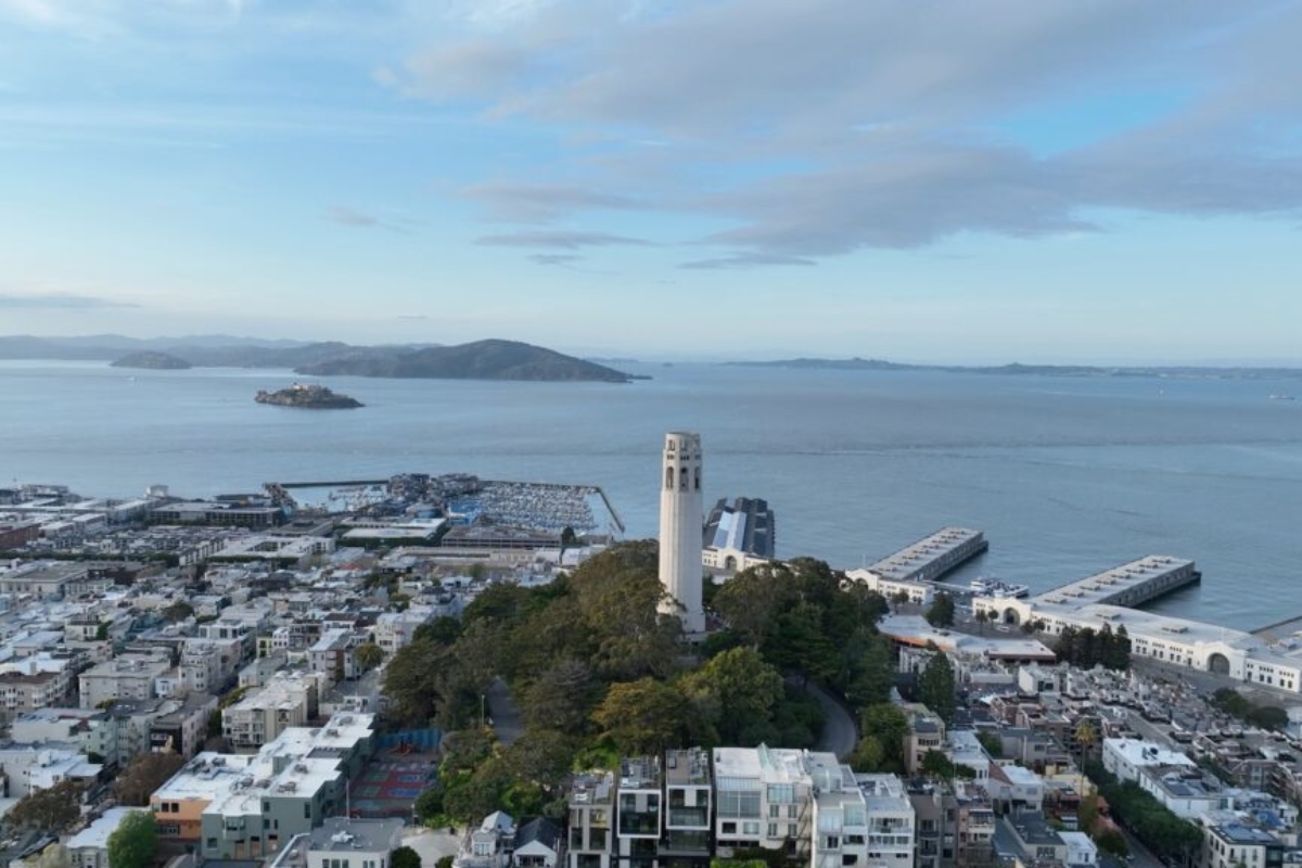 Aerial perspective of Coit Tower on Telegraph Hill overlooking San Francisco's North Beach, marina district, piers, and Bay with Alcatraz Island visible