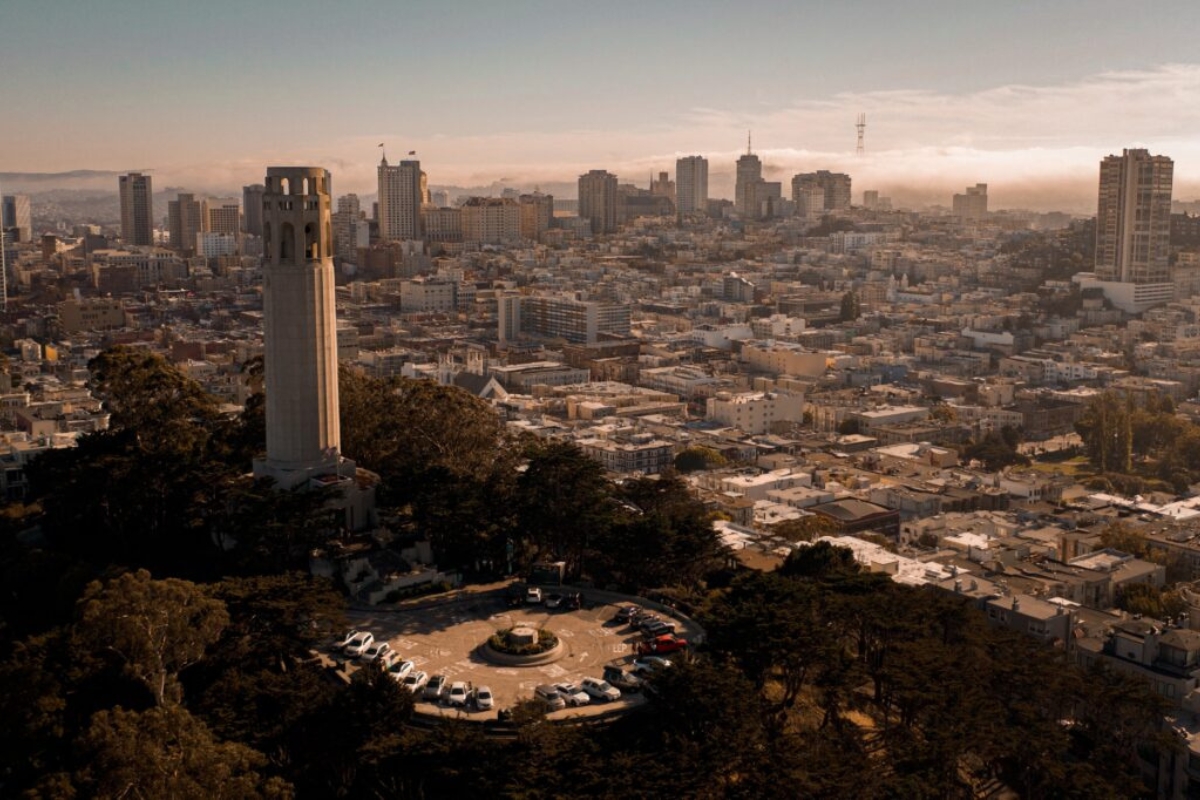 Aerial view of San Francisco downtown skyline from Coit Tower with morning fog, featuring the tower, parking area, and cityscape